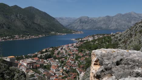 kotor bay, cinematic reveal shot behind stone wall, kotor town, montenegro