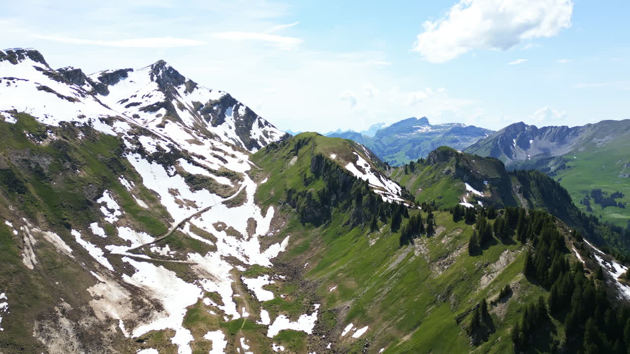 Aerial: mountain above Lake Lioson during the day with snow in Ormont-Dessous, near Les Mosses, in the canton of Vaud, Switzerland, jib up drone shot