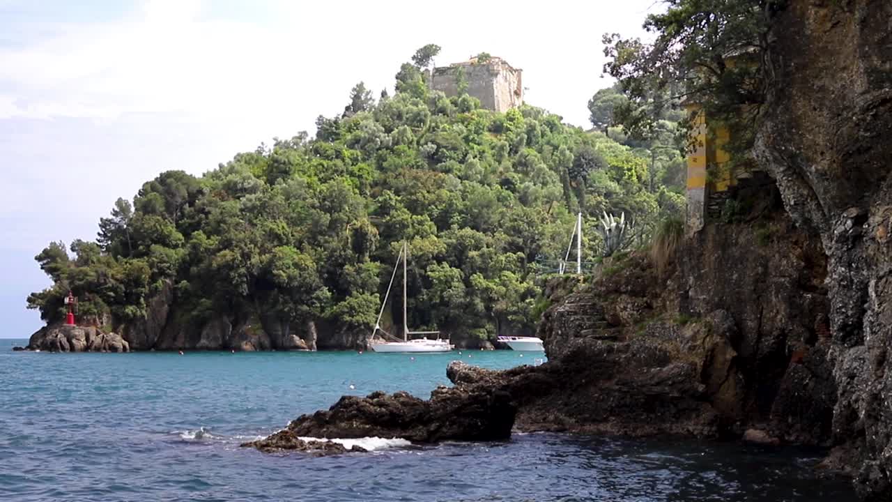 Costa di Portofino, Italia, con barche a vela ancorate e rovine del castello