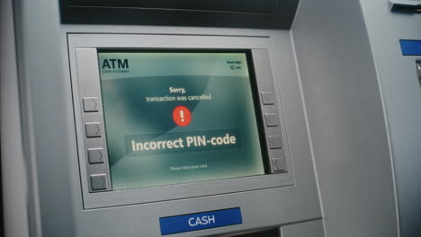 unrecognizable person entering pin code on atm keypad to withdraw money. error message on cash machine display about transaction cancellation due to incorrect pin code. banking equipment. close up.