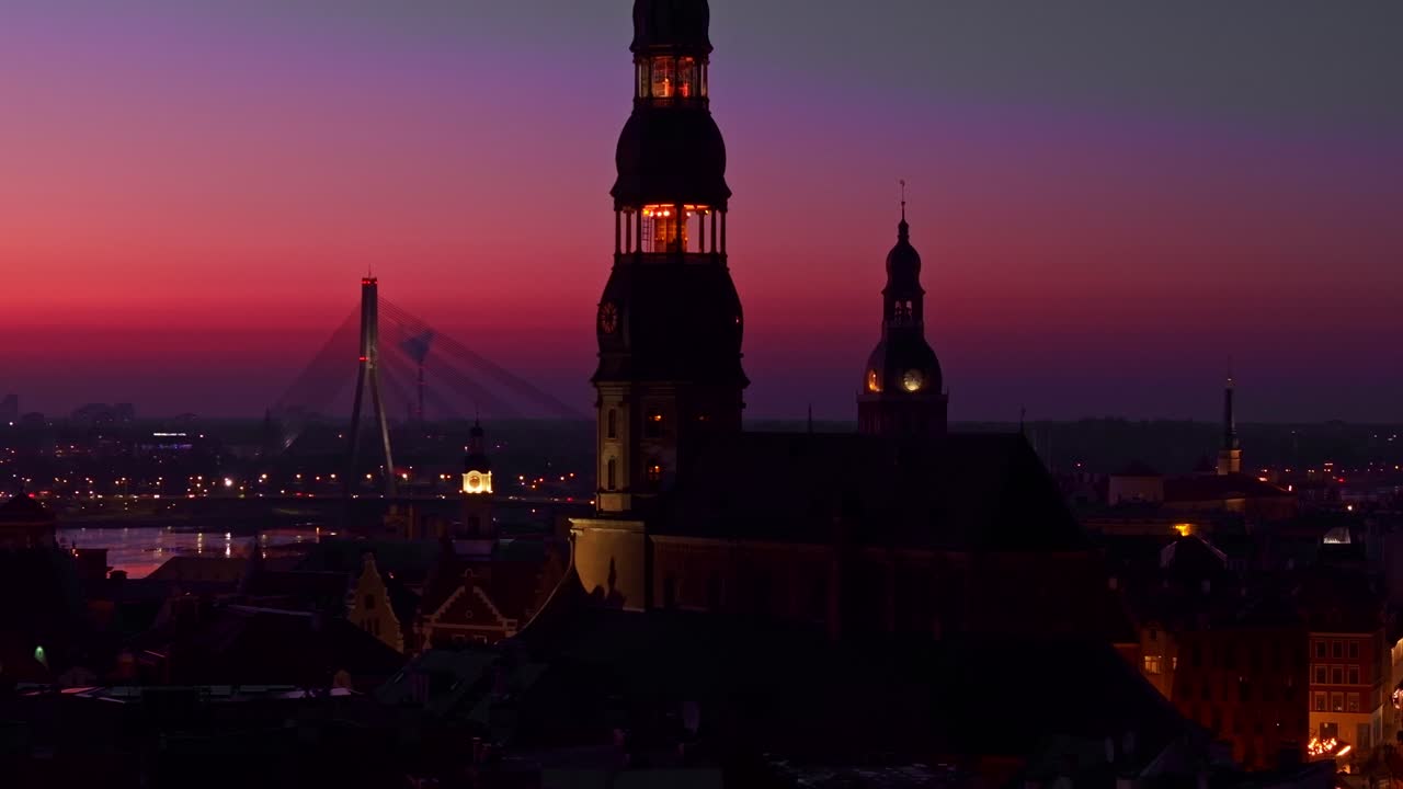 Riga’s skyline glows in deep purple, red hues after sunset over the city, Latvia