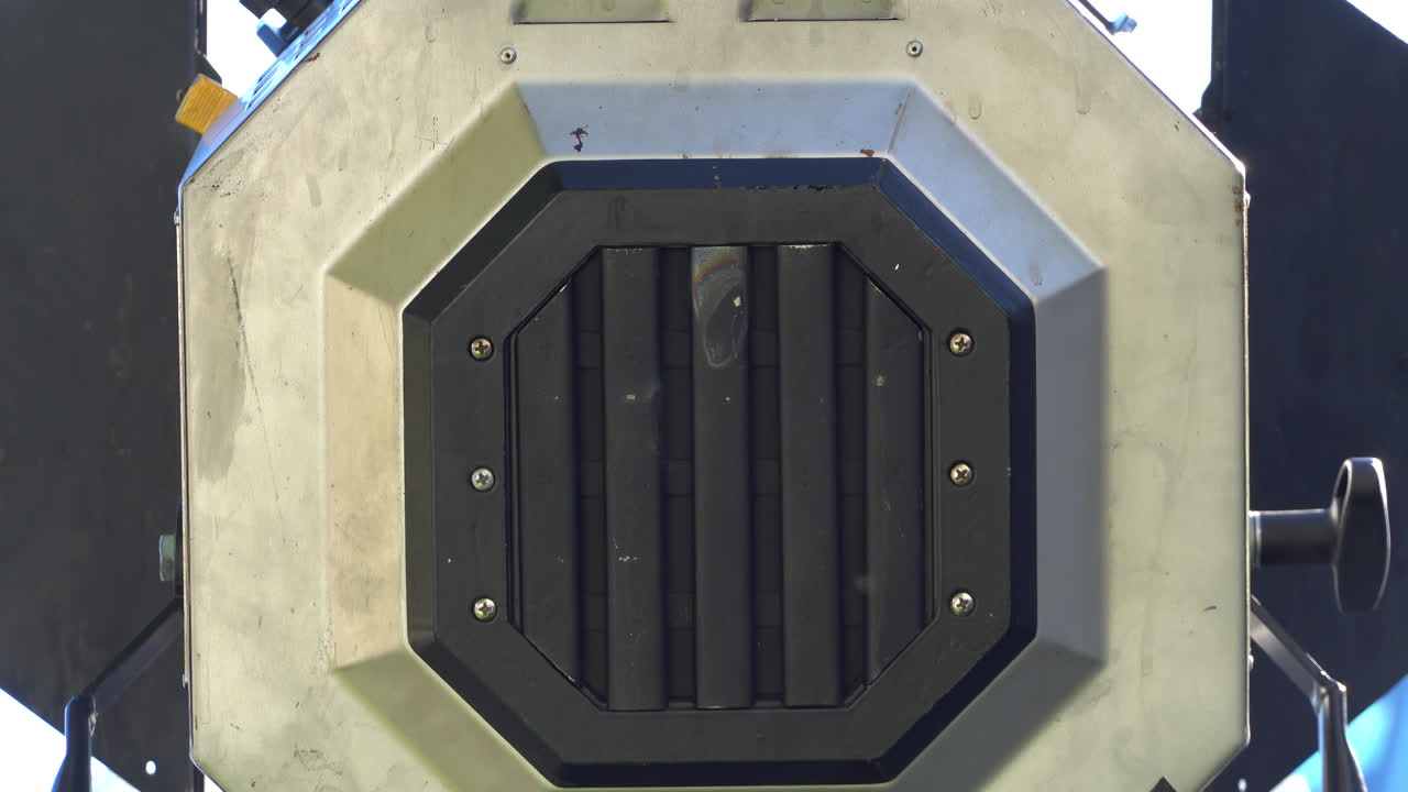 Close-up of a professional film light with set against a clear blue sky and a modern glass building