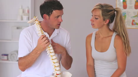 physiotherapist showing his patient a model of the spine