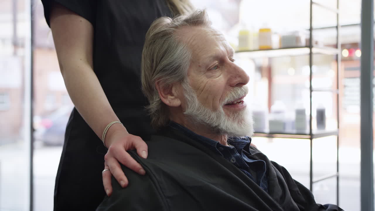 hombre mayor discutiendo corte de pelo con estilista femenina en un salón de peluquería