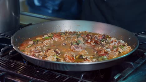 chef vierte caldo en paella española con carne y verduras