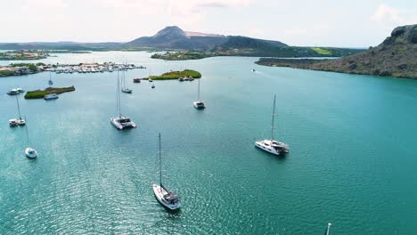 boats and catamarans anchored in water at midday at spanish waters, tafelberg curacao in distance