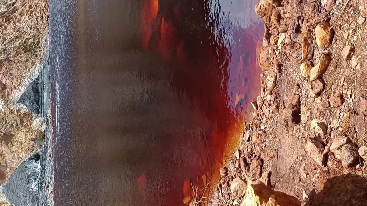 Reddish-Brown Water Flowing Through a Rocky, Barren Landscape