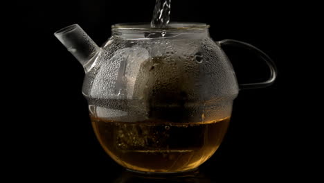 water pouring into glass teapot over loose tea