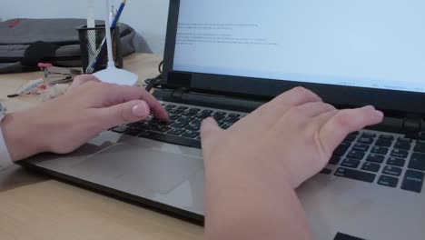 hands typing on a laptop, composing an email, report, or digital content