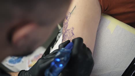 close up footage of tattoo artist demonstrates the process of getting colour tattoo. animalconcept. modern tattoo parlor. top view of tattoo artist and his female client in a beauty salon