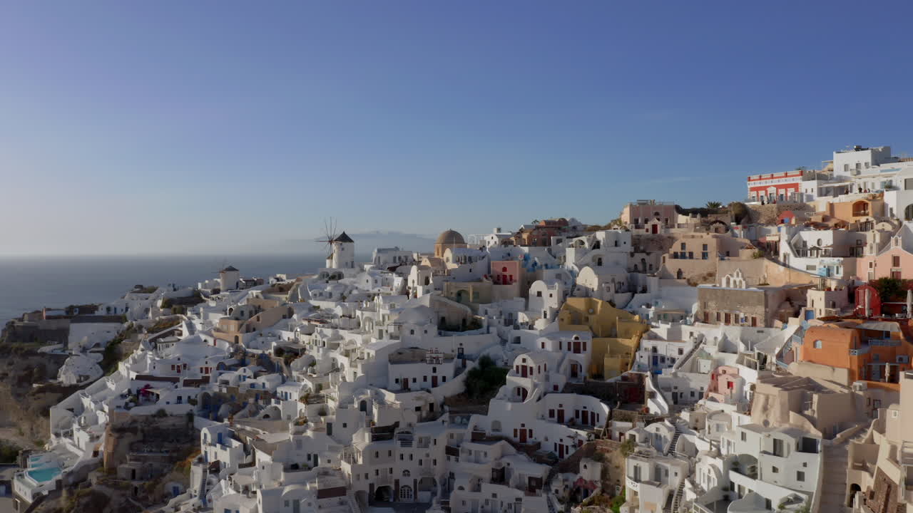 toma panorámica lenta de oia en santorini, grecia durante la hora dorada