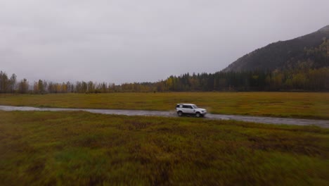 landrover defender driving offroad through puddles as drone pushes in