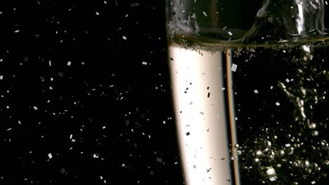 animation of confetti over champagne pouring into glass on black background