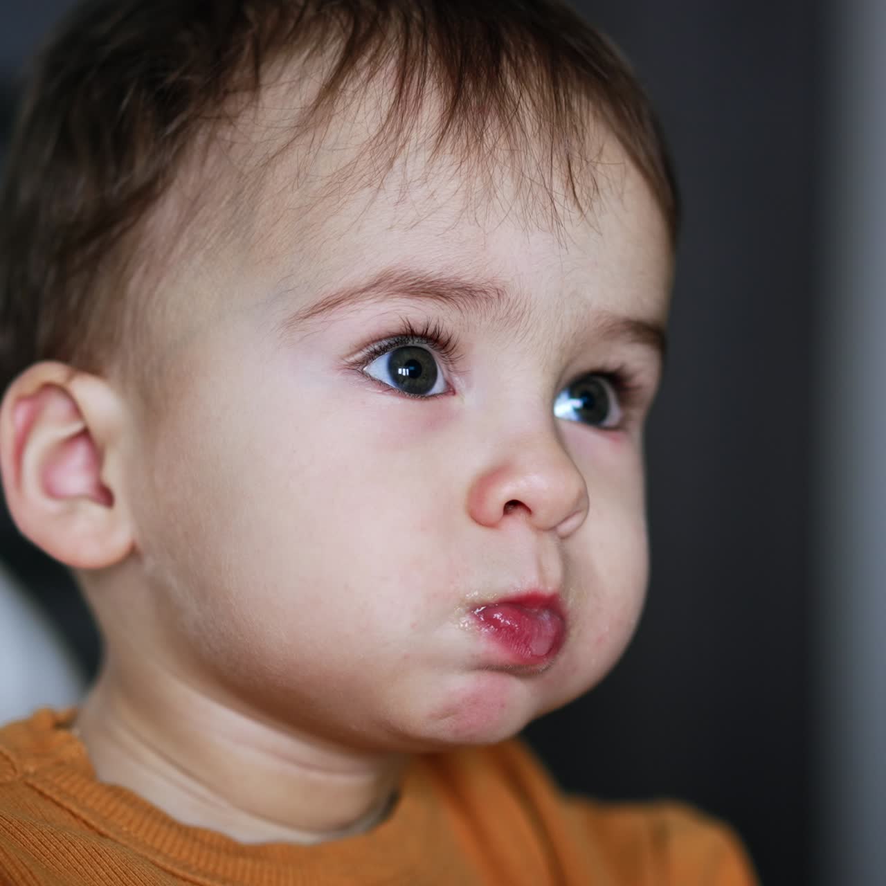 Beautiful baby being fed from spoon. Adorable kid opens mouth wide and chewing food well. Close up