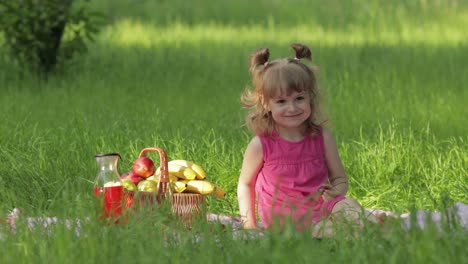 Weekend-at-picnic.-Lovely-caucasian-child-girl-on-green-grass-meadow-eating-merry,-cherry