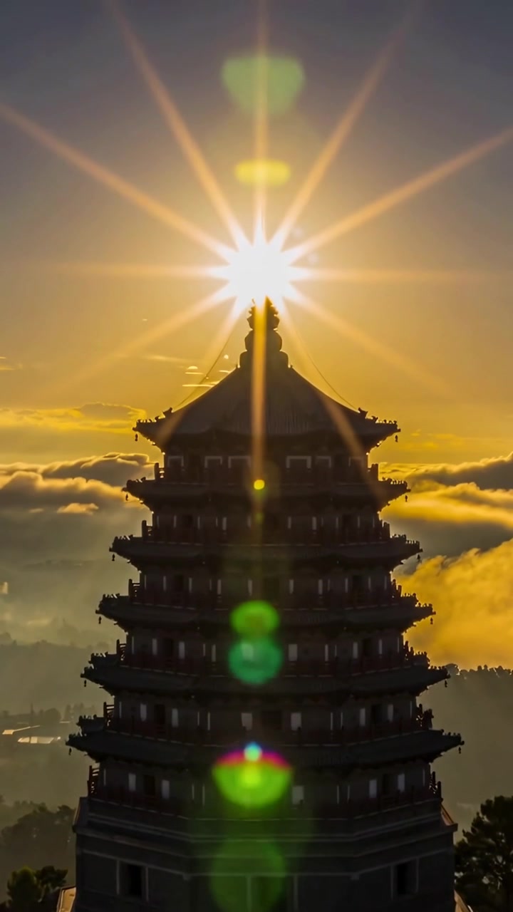 Video vertical: Sol ascendente iluminando una pagoda en la cima de una colina y produciendo destellos de lente verdes sobre la aguja.