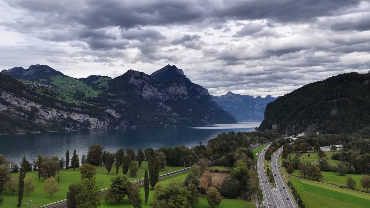 The dramatic Walensee and towering Alpine peaks contrast with the highway and green fields below in Schweiz. Concept of nature's majesty meeting modern infrastructure