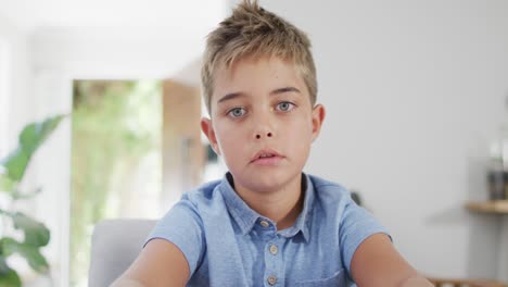 Happy-caucasian-boy-sitting-at-table,-having-online-lesson,-slow-motion