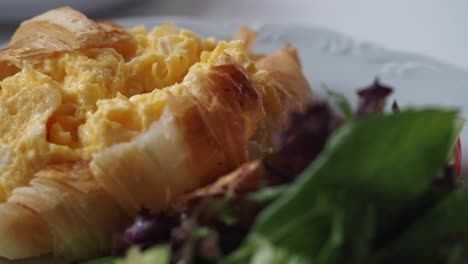 croissant with scrambled eggs and salad
