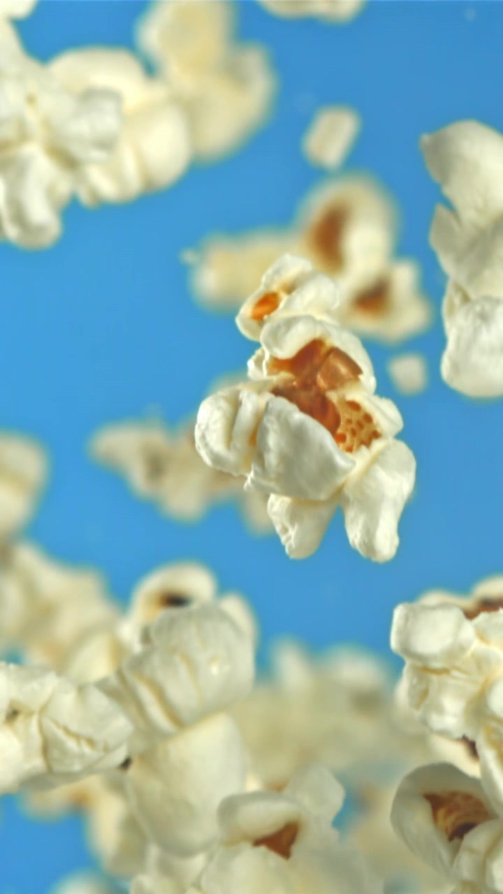 Popcorn falder i slowmotion mod en blå baggrund
