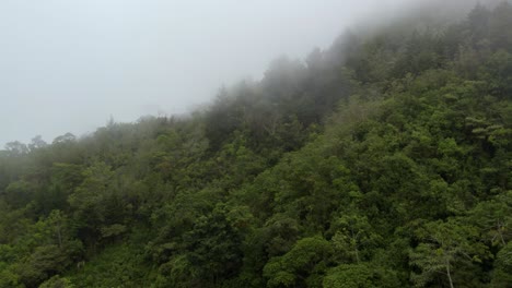 Aerial-dolly-in-of-Chirripo-green-dense-forest-hillside-covered-in-white-foogy-clouds,-Canaan-de-Rivas,-Costa-Rica