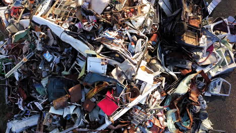 Mounts-of-car-scraps-on-a-junkyard,-doors,-wheels,-several-parts-of-wrecked,-dented-cars