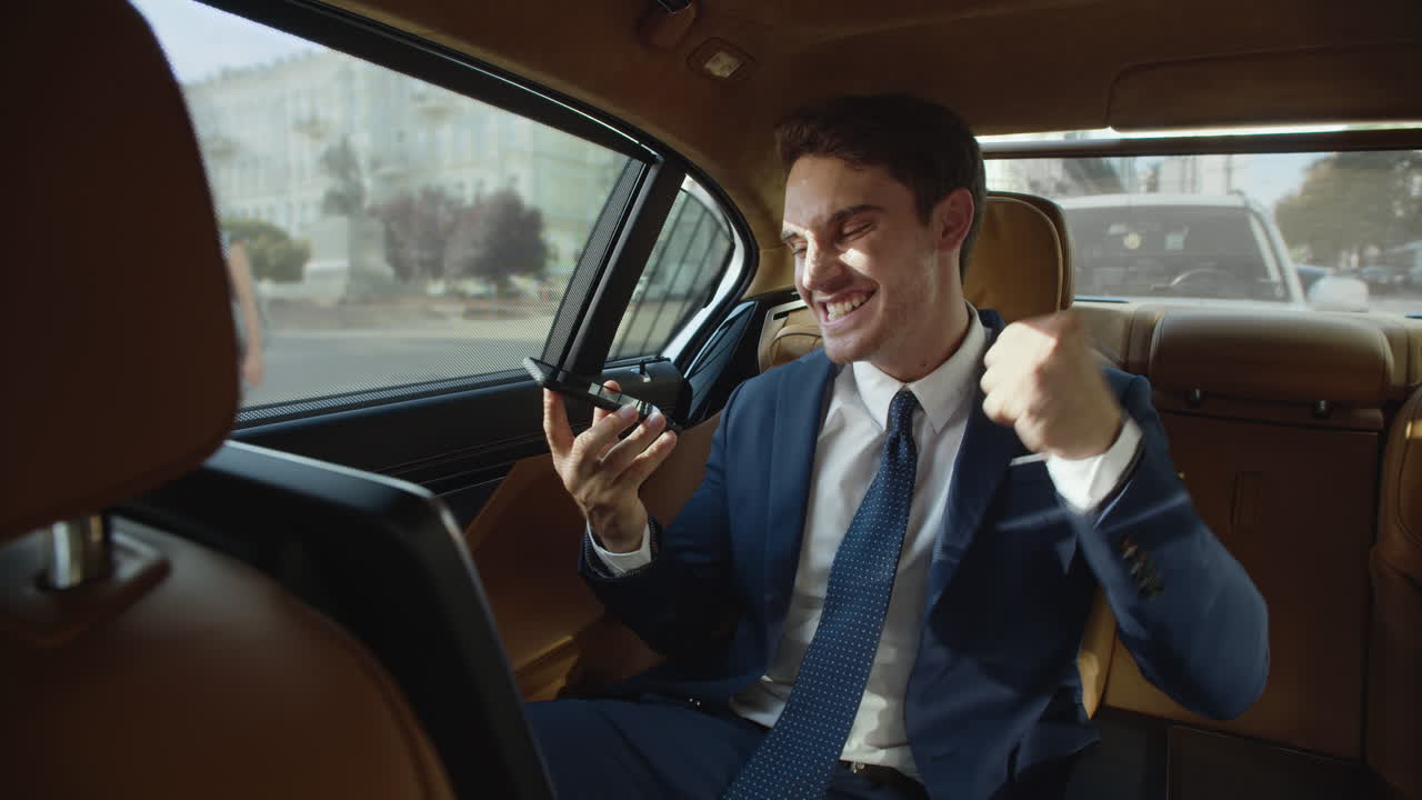 hombre de negocios feliz compartiendo alegría en el mensaje de voz al teléfono móvil en el coche de negocios.