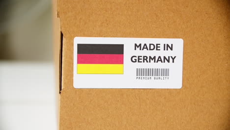 hands applying made in germany flag label on a shipping cardboard box with products