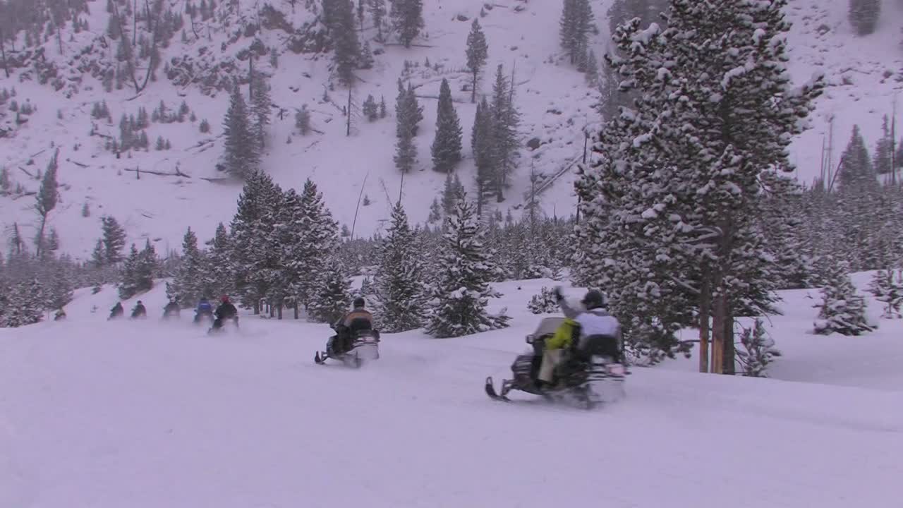 Una lunga fila di motoslitte si avventura attraverso un paesaggio innevato