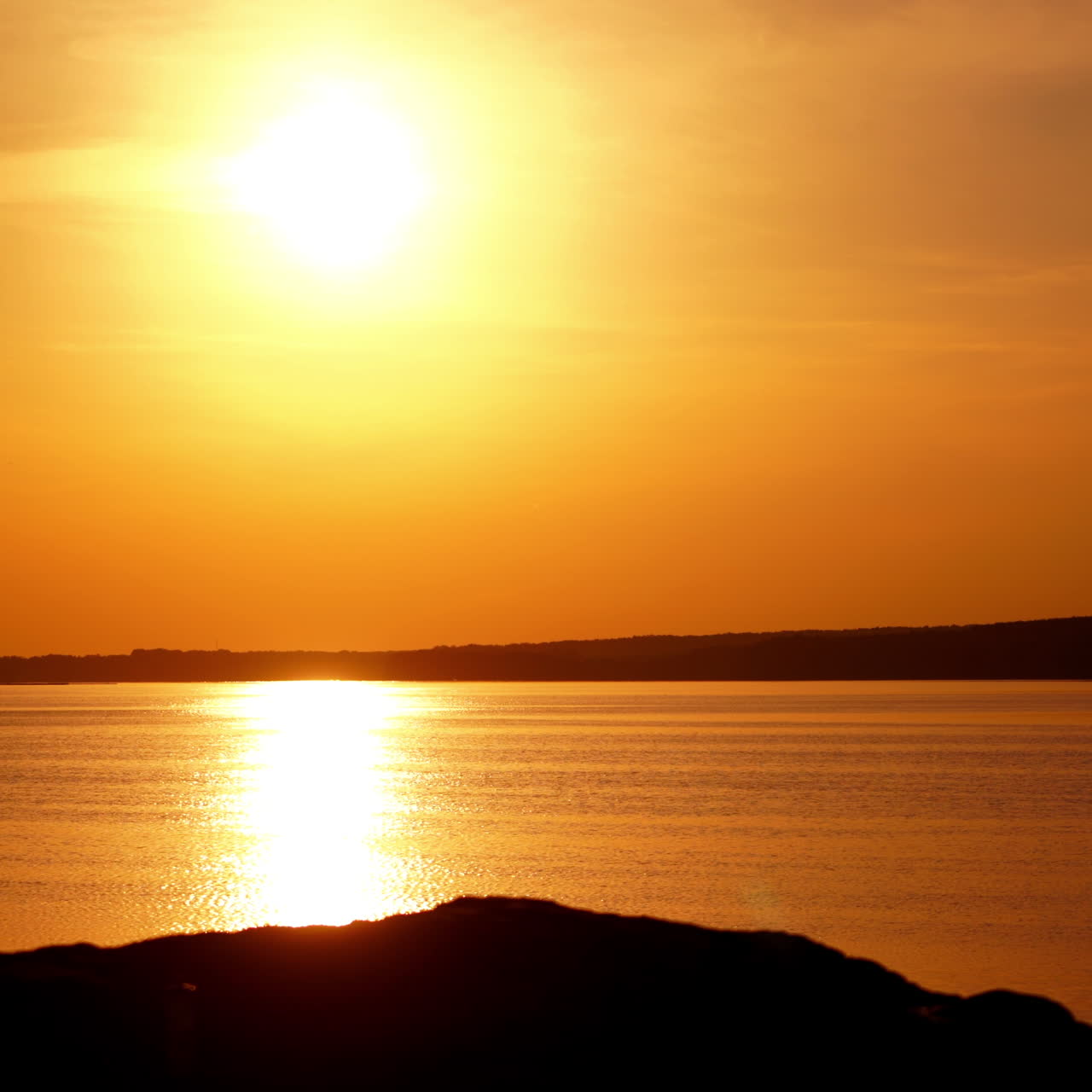 Silhouette of a male cyclist with helmet at sunset near the river. Bike rider walks with his bike on the background of the golden path from the sun over the water surface.