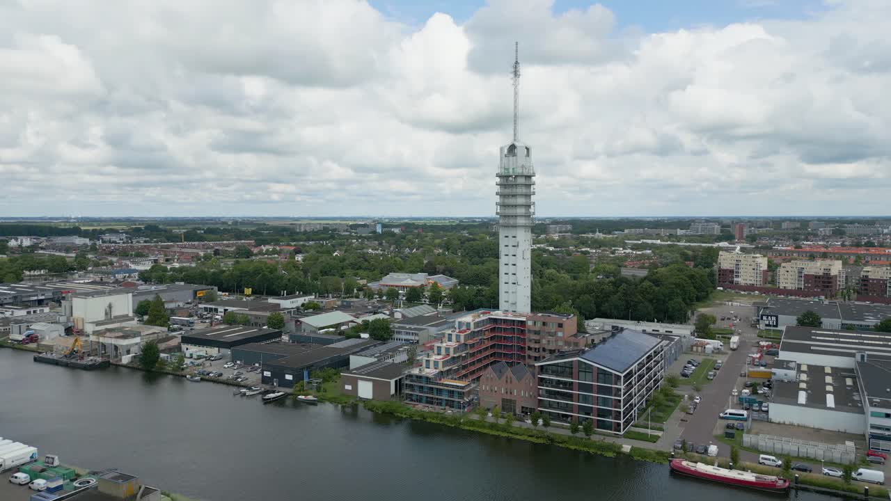 Striking vertical tower surrounded by warehouses and a canal in Alphen aan den Rijn, filmed from above