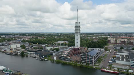 striking vertical tower surrounded by warehouses and a canal in alphen aan den rijn, filmed from above