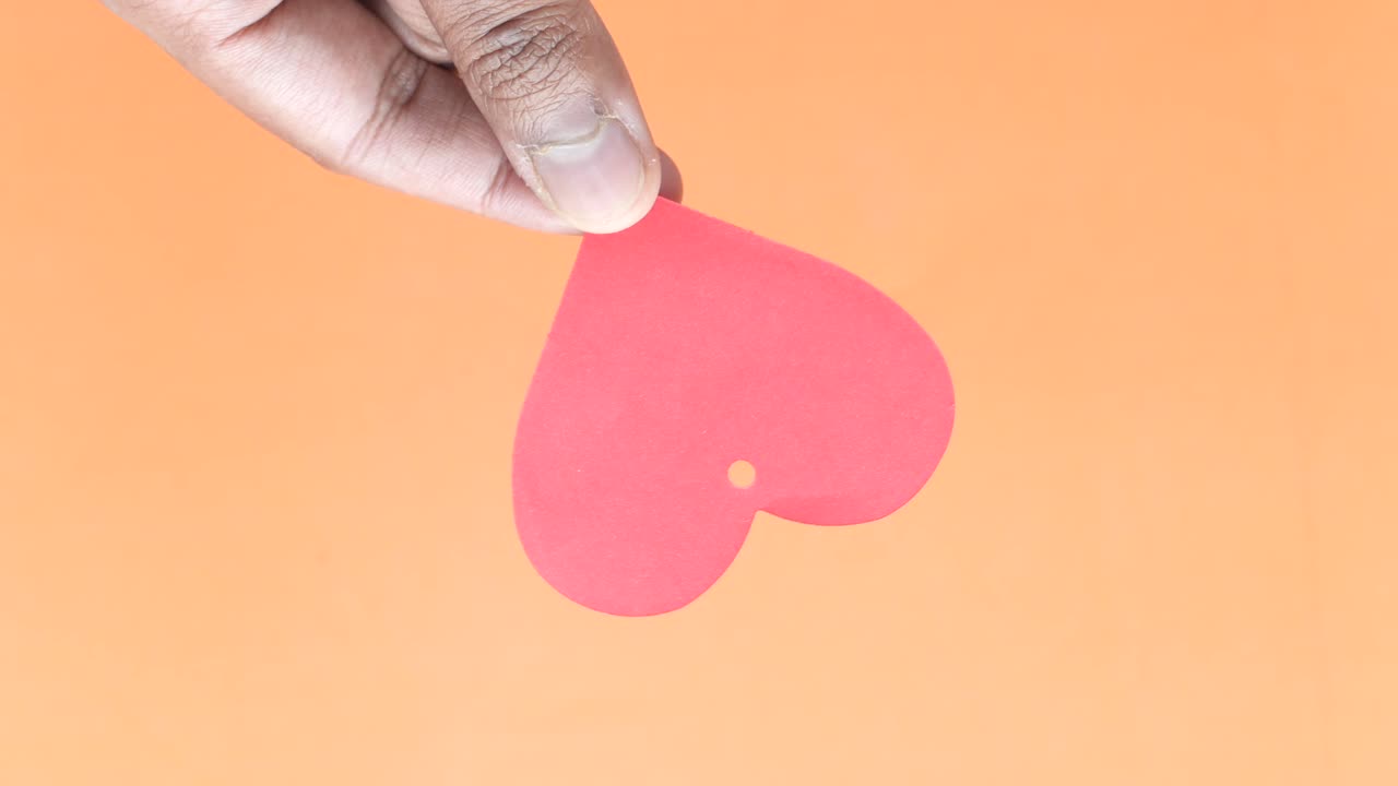 mano con un corazón de papel rojo
