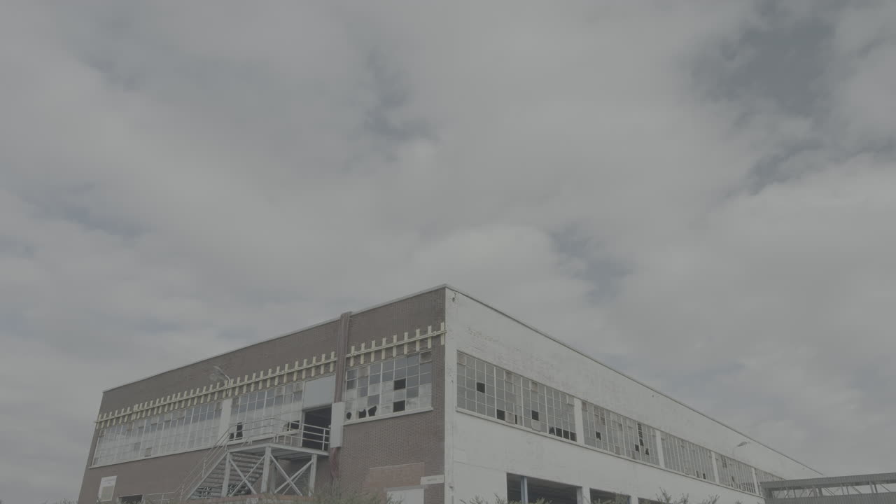lapso de tiempo de nubes flotando sobre un viejo edificio de estacionamiento con ventanas rotas y vidrio que refleja el cielo en un registro de día nublado