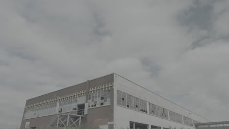 lapso de tiempo de nubes flotando sobre un viejo edificio de estacionamiento con ventanas rotas y vidrio que refleja el cielo en un registro de día nublado