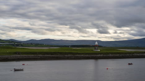 Time-lapse-of-lighthouse-harbor-with-parked-boats-in-foreground-and-fast-moving-clouds-in-the-sky-in-Ireland