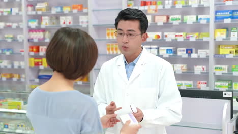 cheerful pharmacist smiling presenting and recommending medical pills in blister in a pharmacy store drug