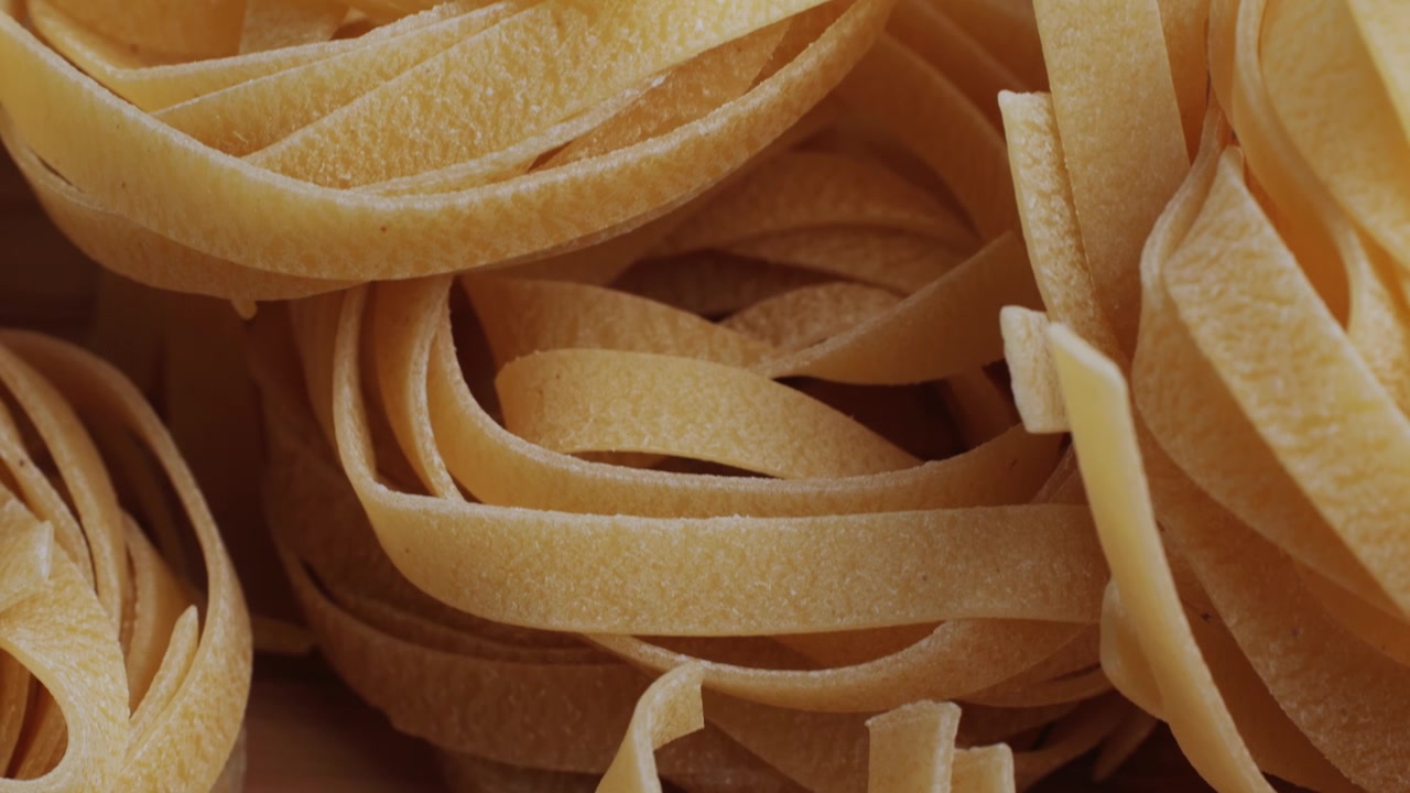Primo piano di nidi di tagliatelle secche su una superficie di legno