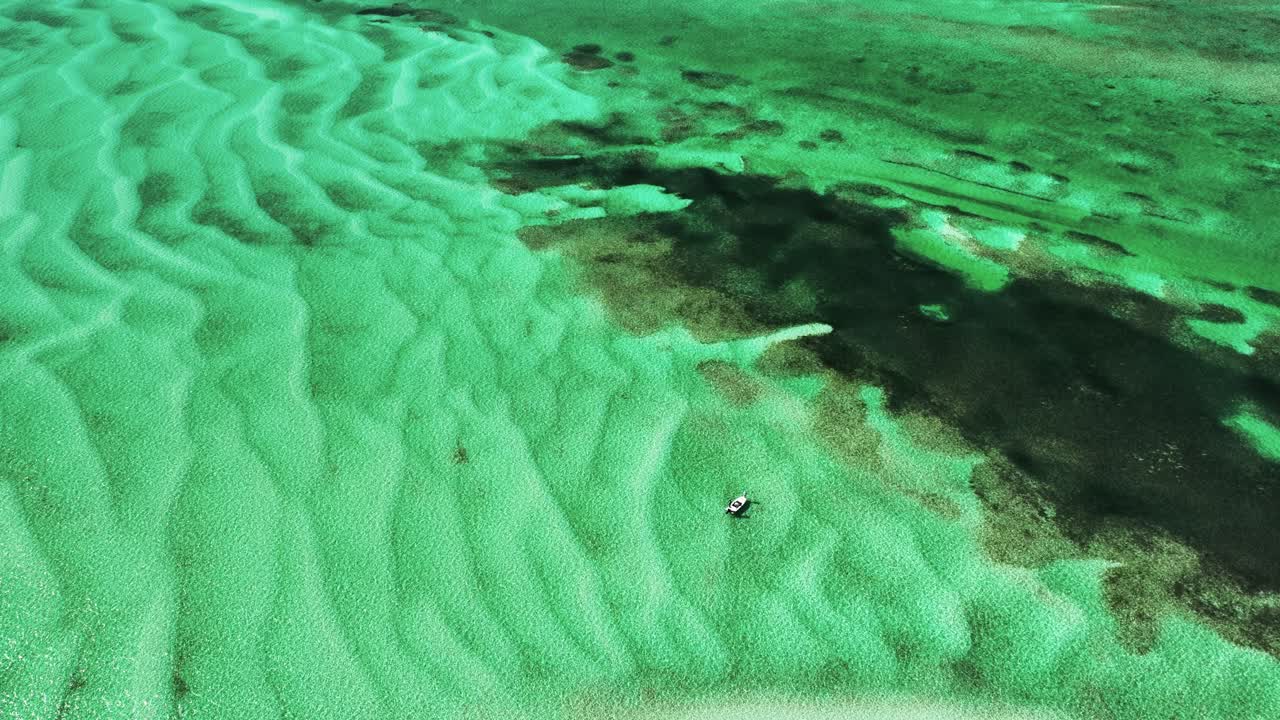 Luftfoto af fiskebåd nær koral, hvide krusninger på Bahamas' lavvandede område.