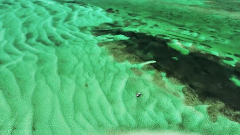 aerial shot of fishing boat near coral, white ripples on bahamas flat