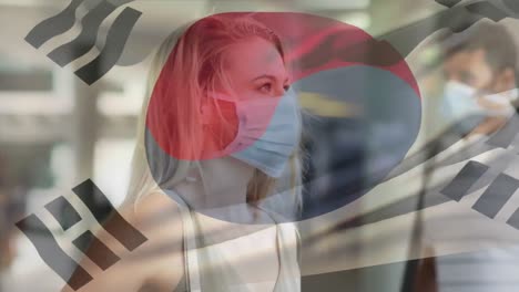 Animation-of-flag-of-korea-waving-over-woman-wearing-face-mask-during-covid-19-pandemic