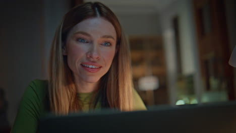 closeup late worker looking laptop screen with smile at evening apartment.