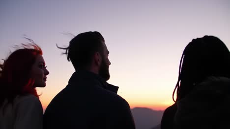 a group of friends enjoying a sunset view together, silhouetted against the colorful sky as they share a moment of connection and tranquility in nature's beauty