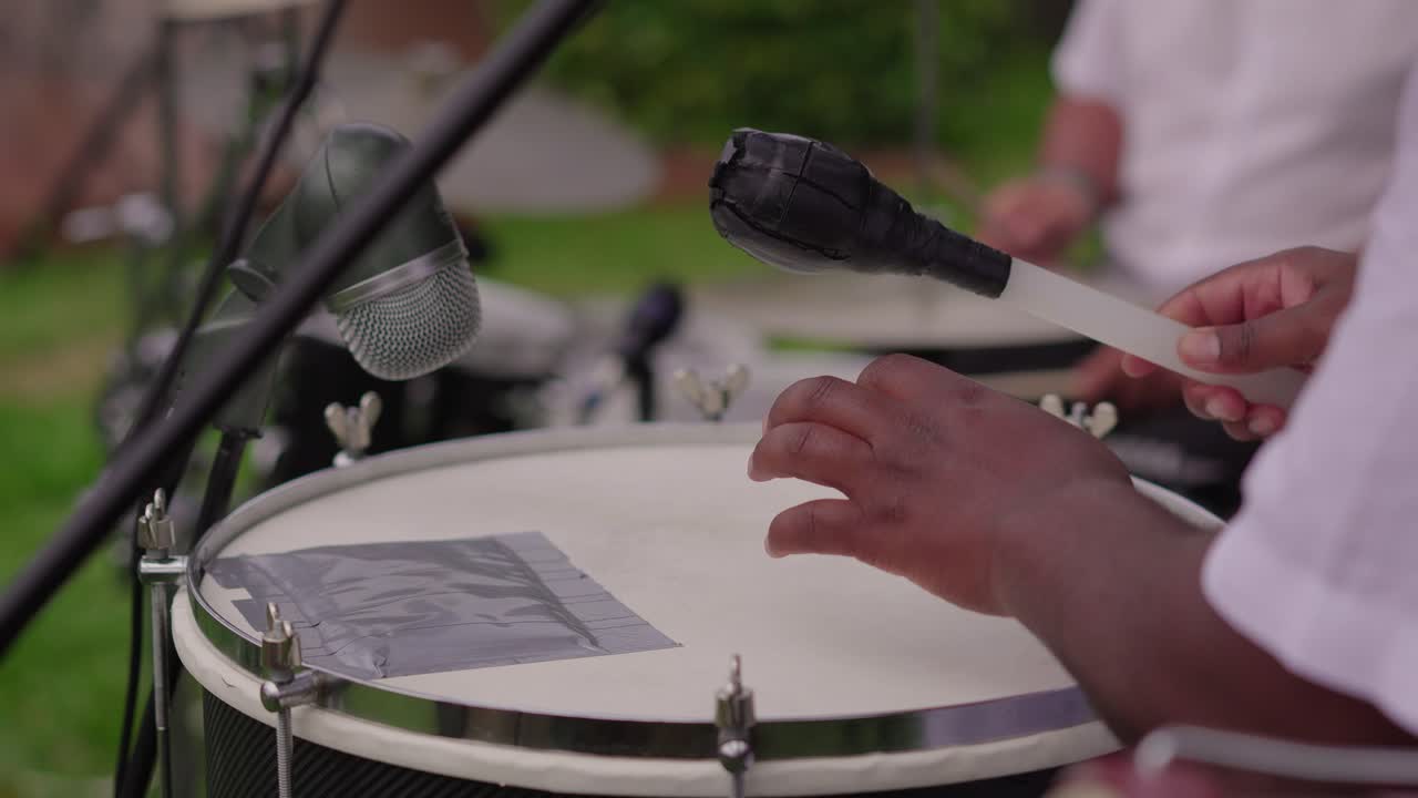 Close-up of hands striking drum with mallet during live performance