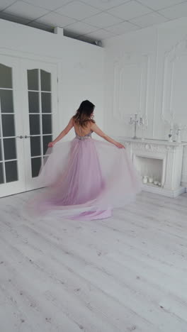 young model in wedding dress is spinning happily in a spacious room. romantic bride is posing in a hotel room in her wedding dress. vertical video