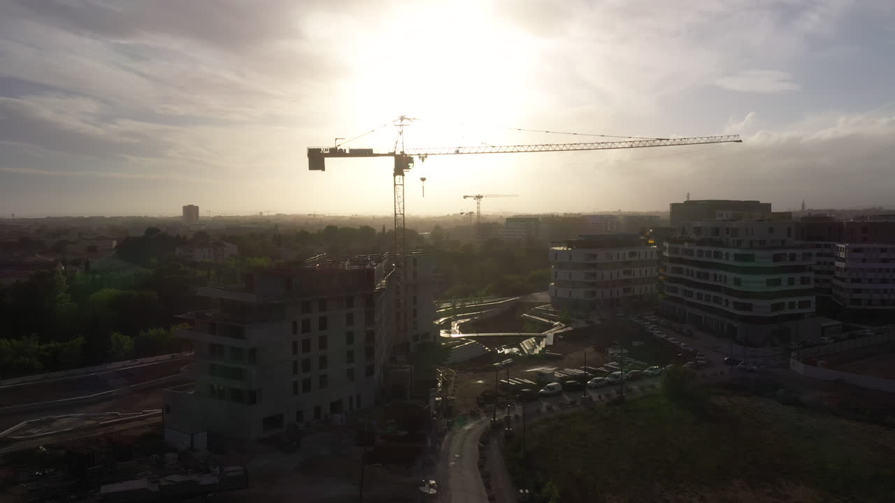 silueta de la grúa de construcción durante la puesta del sol aérea de montpellier rive du lez port