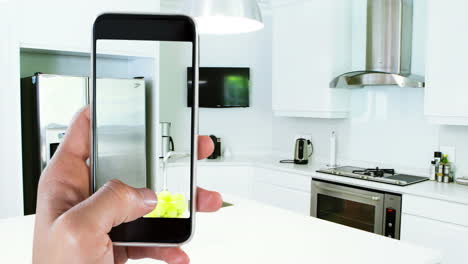 persona que sostiene un teléfono inteligente con interiores de cocina modernos mostrados en la pantalla