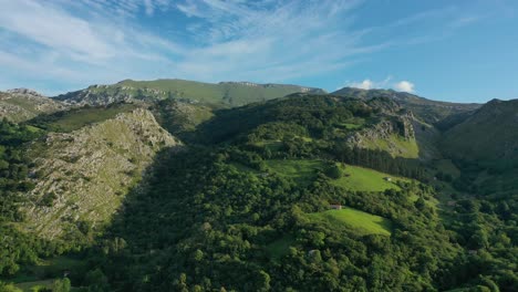 vuelo lateral con un dron en las montañas de piedra caliza son bosques de robles y hayas viendo pendientes escarpadas casas de ganado prados verdes y picos de meseta en un día de verano en cantabria-españa