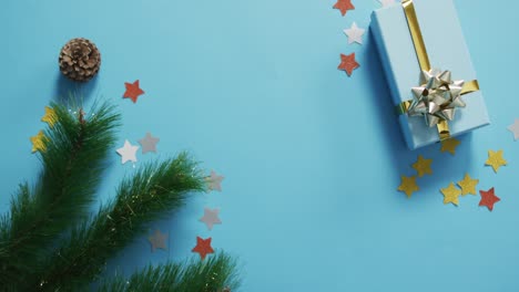 video of christmas decorations with present and copy space on blue background