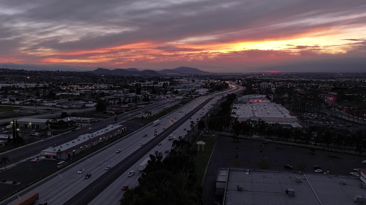 바뀌는 구름과 함께 놀라운 역동적인 일몰 캘리포니아 고속도로 10 위에 오렌지색과 분홍색과 바쁜 교통 장면은 해가 지면 점점 어두워집니다.